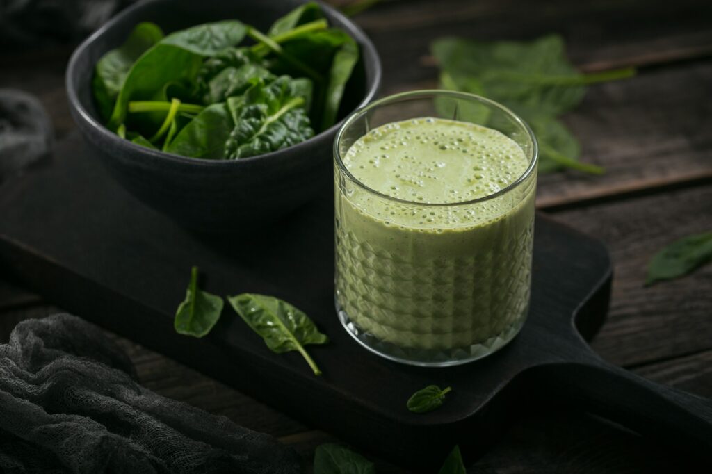 Glass of homemade healthy green smoothie with fresh baby spinach