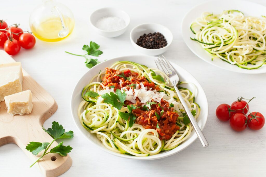 keto paleo zoodles bolognese: zucchini noodles with meat sauce and parmesan