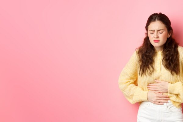 Young woman with pain in stomach, holding hands on belly, feeling terrible ache, menstrual cramps