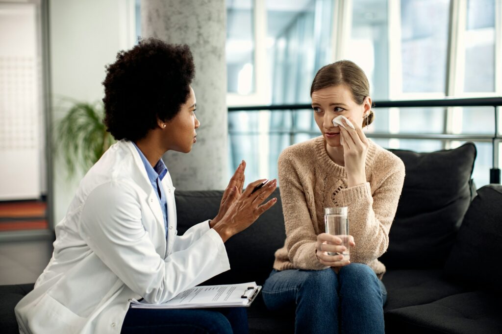 African American counselor talking to a crying woman during psychotherapy session.