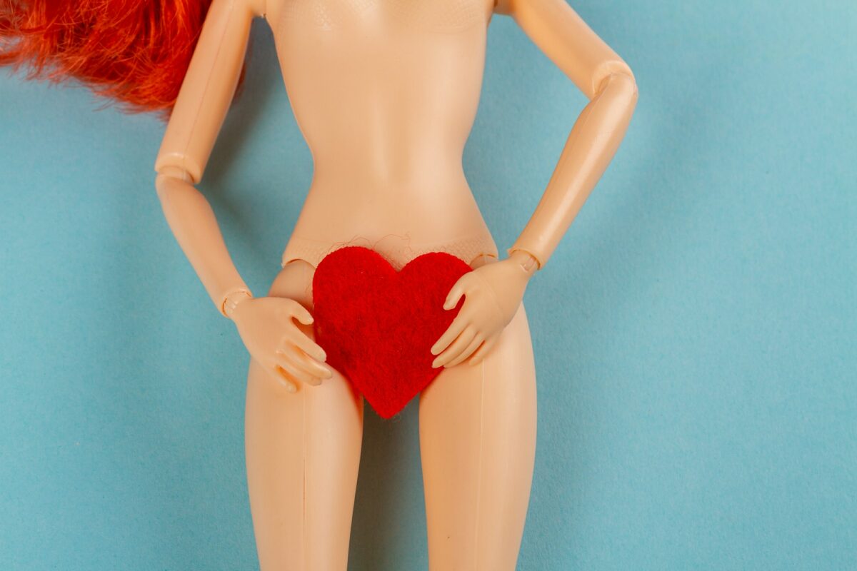 Naked female doll with red heart covering her groin.