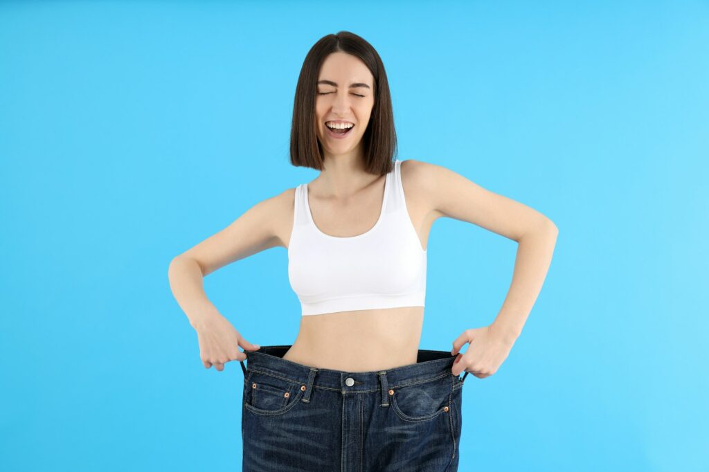 Concept of weight loss with young slim woman on blue background